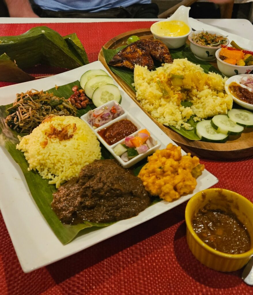 Indonesian rice platter with yellow rice, rendang, grilled chicken, sambal and side dishes on banana leaves at Ruby’s Cafe, Gili Air