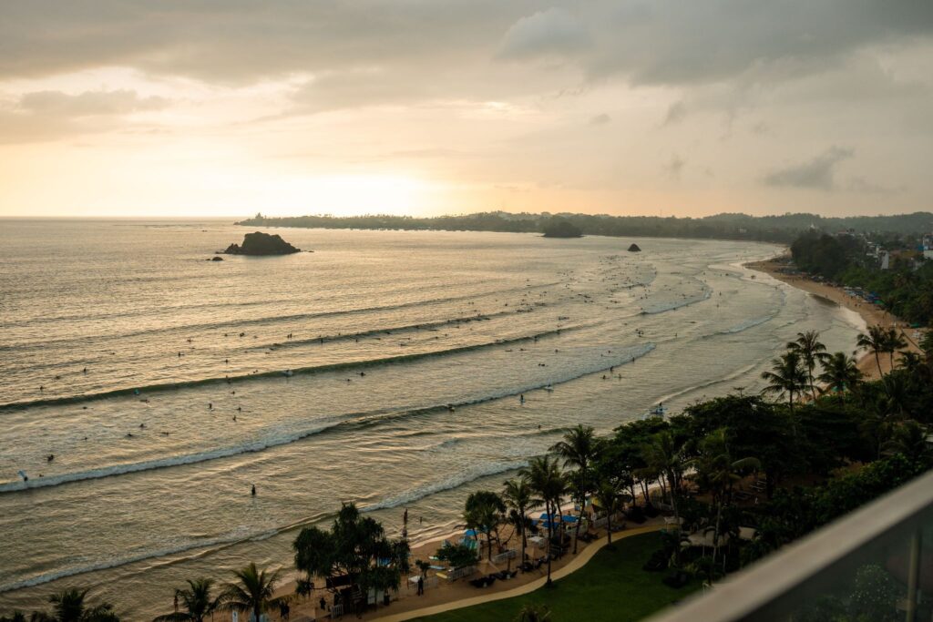 Weligama Bay in Sri Lanka from above at sunset, with surfers in the water