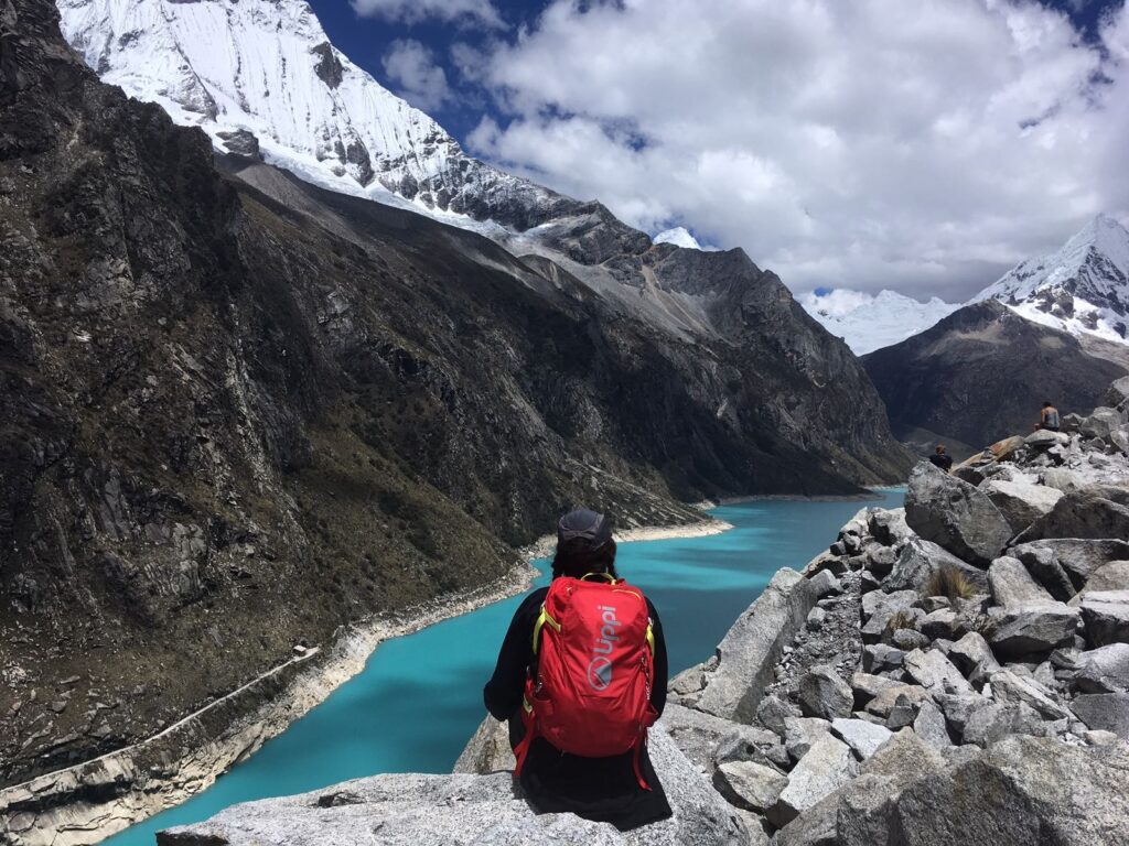 Laguna Parón Huaraz Peru turquoise glacial lake snow capped mountains with a backpacker