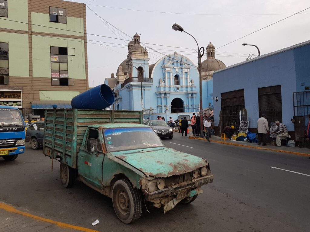 The streets of Lima Peru with a rusted truck and a blue church