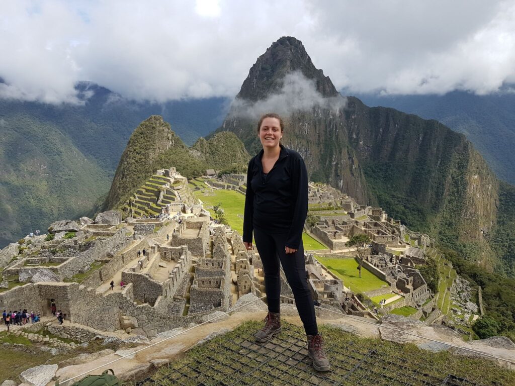 Machu Picchu experience: hiker standing in front of the ruin with Huayna Picchu and clouds in the background